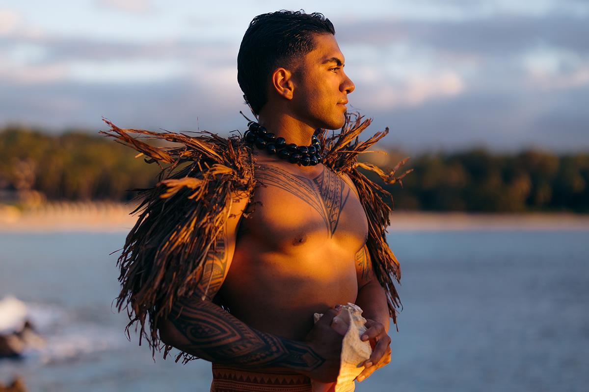 A man looking out at the ocean holding a conch shell