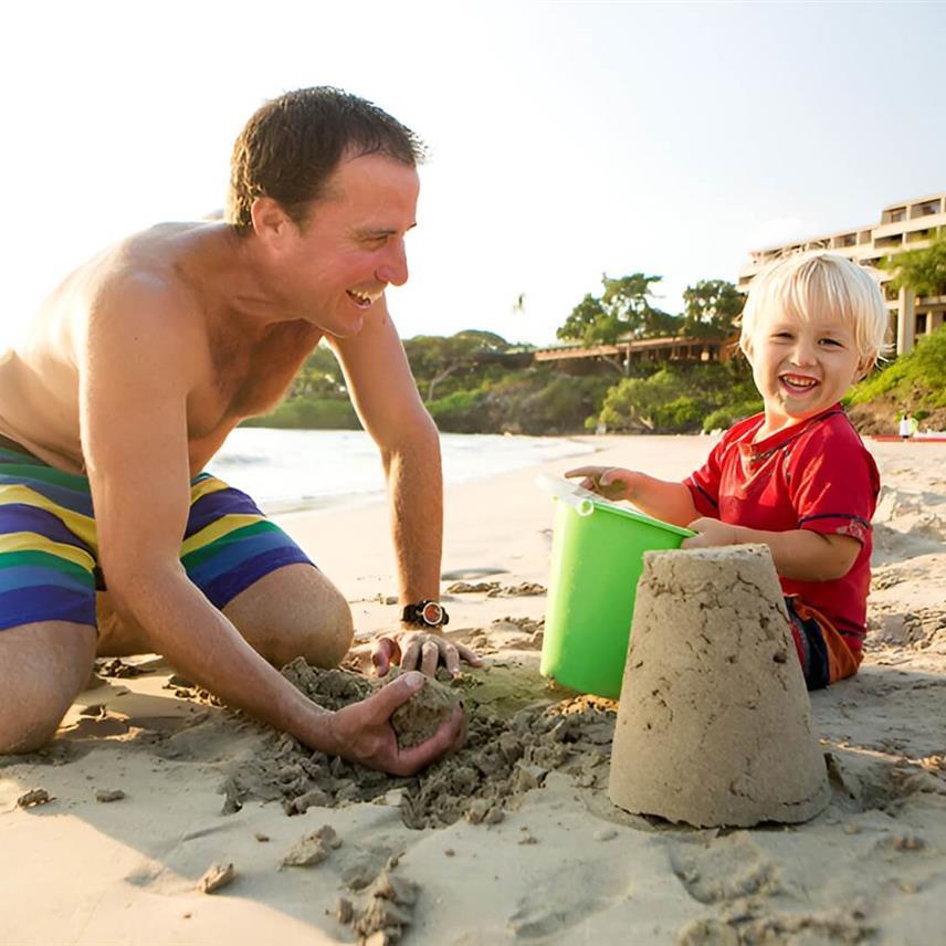 A father and son play on the beach